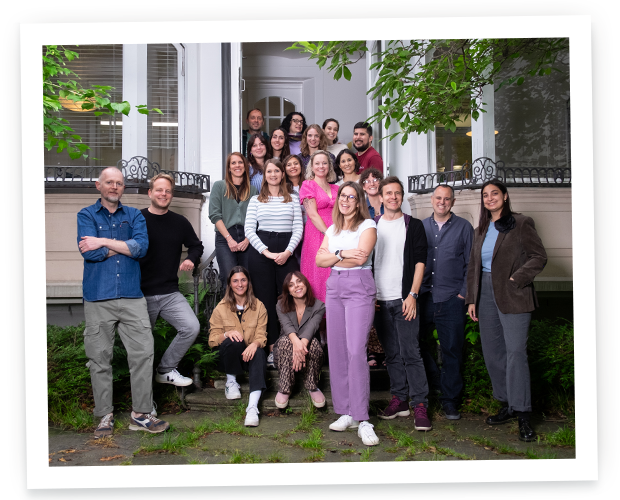 Une photo de groupe d'une équipe diversifiée de collègues souriant ensemble à l'extérieur sur les marches d'un bâtiment blanc classique.