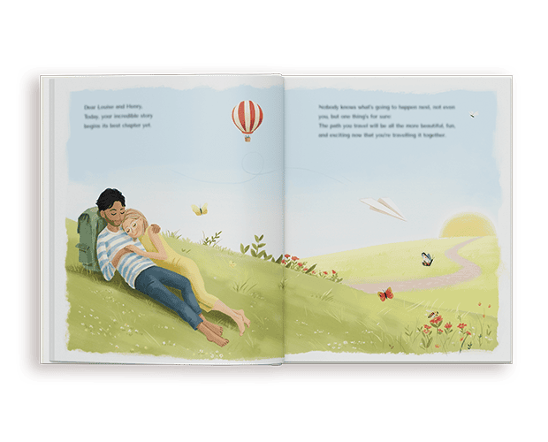 Un libro de bodas personalizado abierto que muestra una hermosa ilustración de una pareja relajándose junta en una colina verde bajo un cielo azul claro con un globo aerostático.